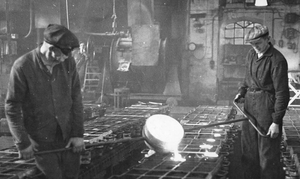Historisk bilde av to menn arbeider med jern på Jernværket. Foto.