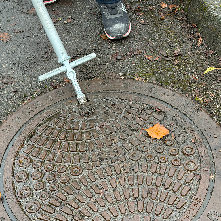 Renser spetthull på kumlokk med kumkrok. Foto.